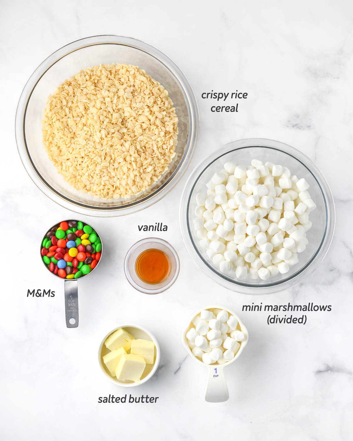 all 5 ingredients to make the rice krispie treats shown from above in bowls and measuring cups.