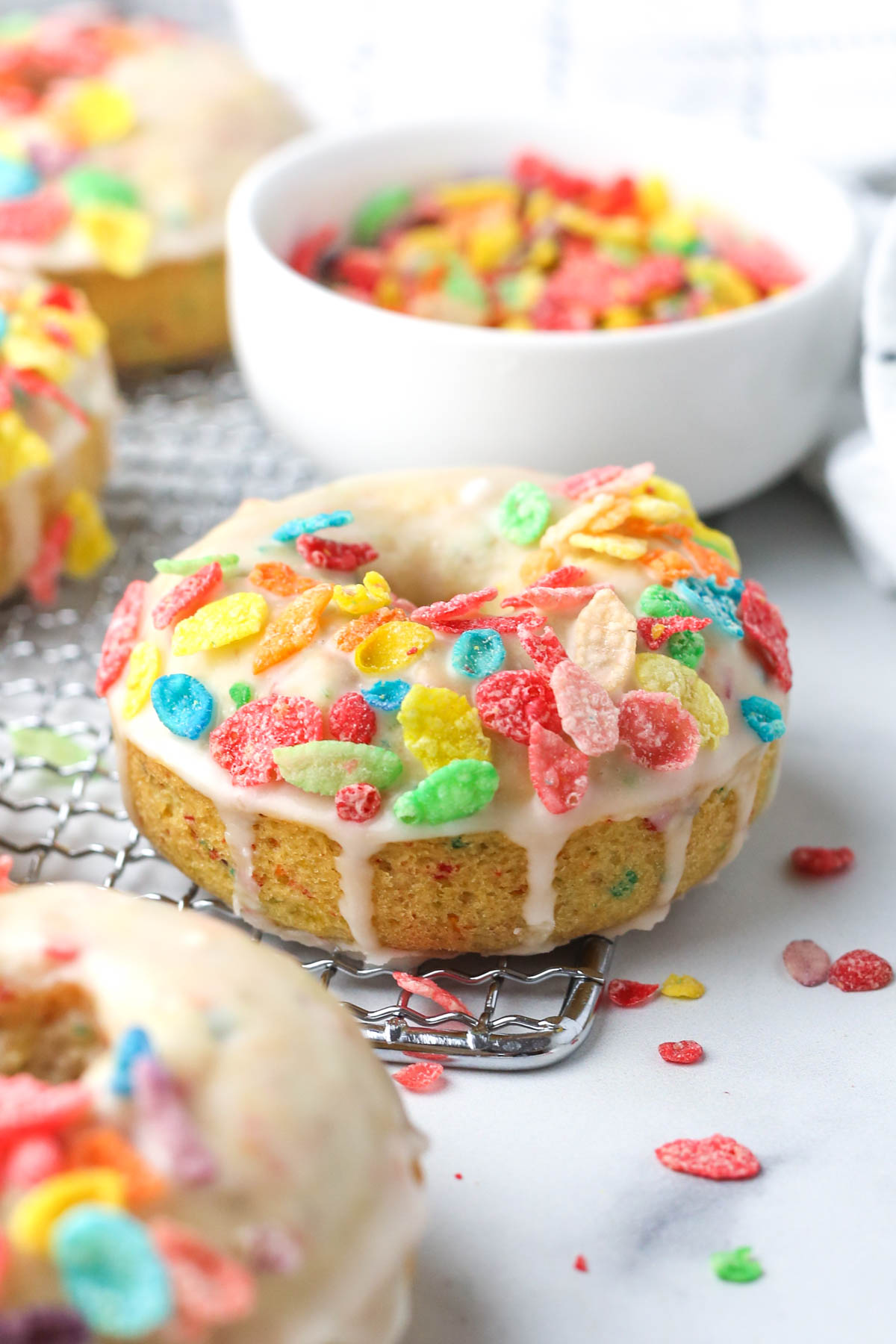 Side view of a donut with icing dripping down the edges and fruity pebbles on top.