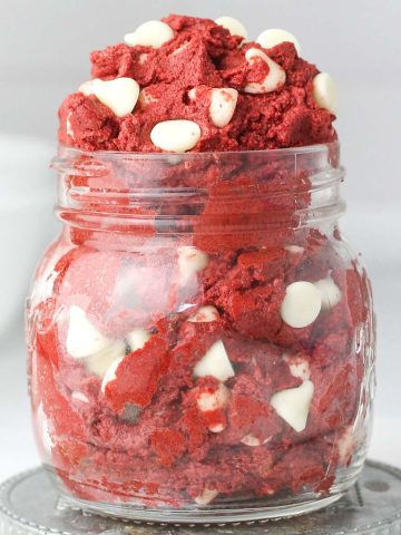 A jar filled with edible red velvet cookie dough and white chocolate chips.