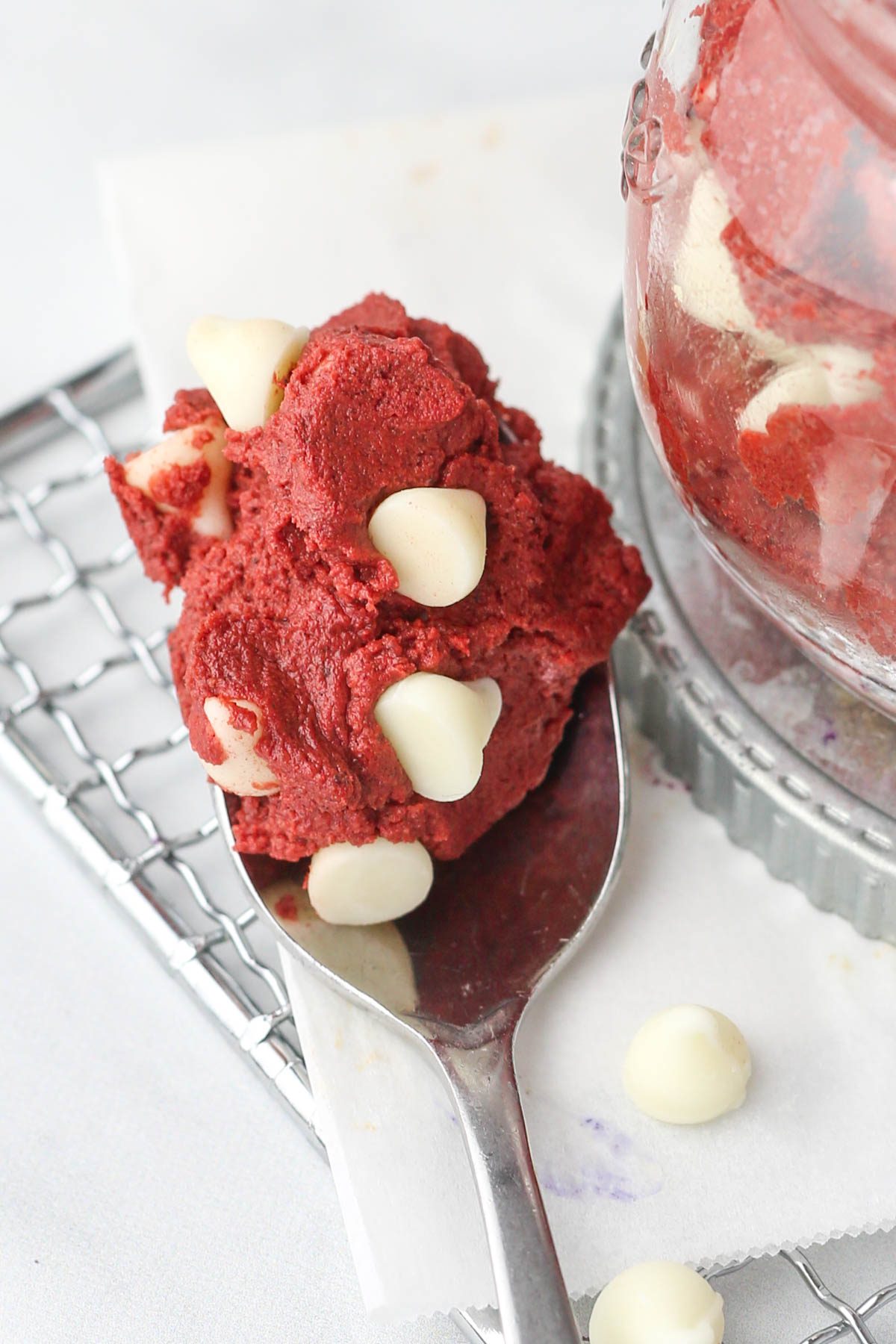 A spoonful of red velvet dough with white chocolate chips.