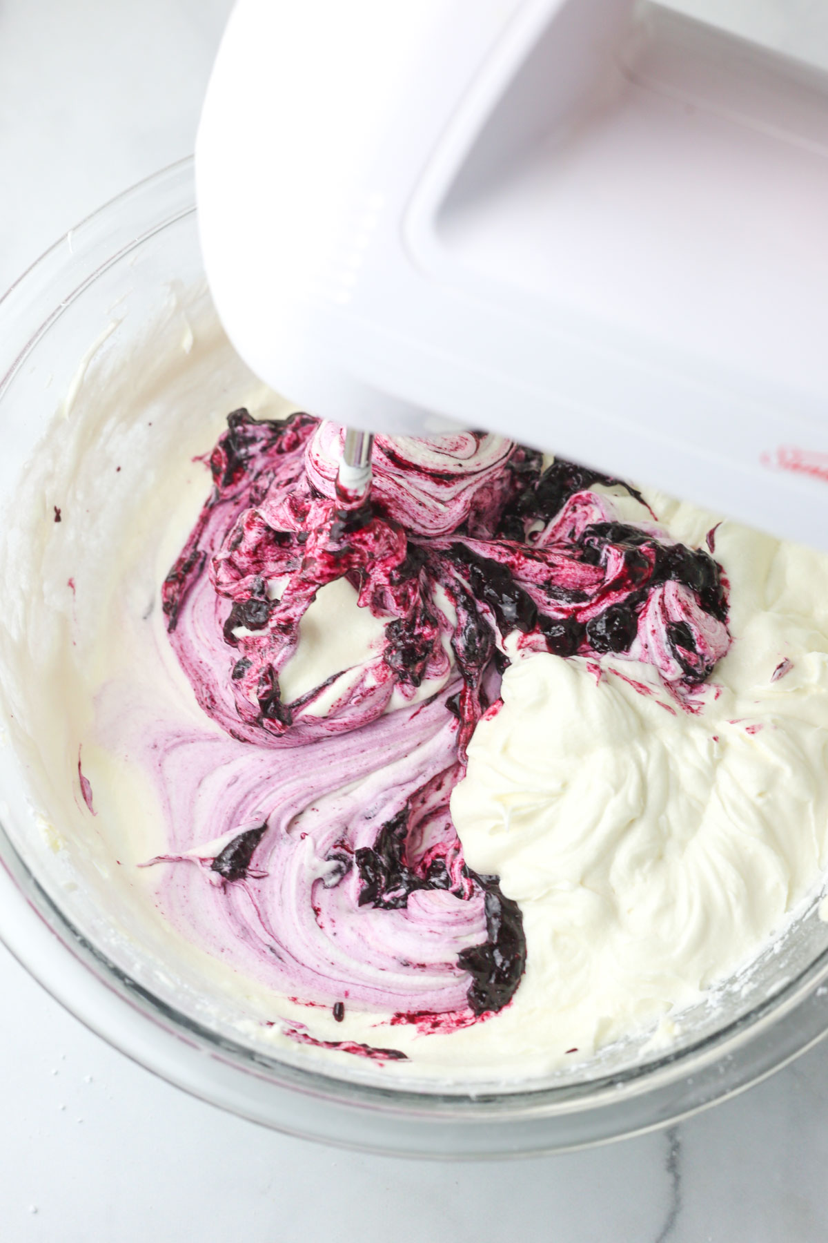 Mixing the blueberry sauce into the cream cheese frosting.