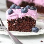 A square slice of blueberry chocolate cake with purple frosting.