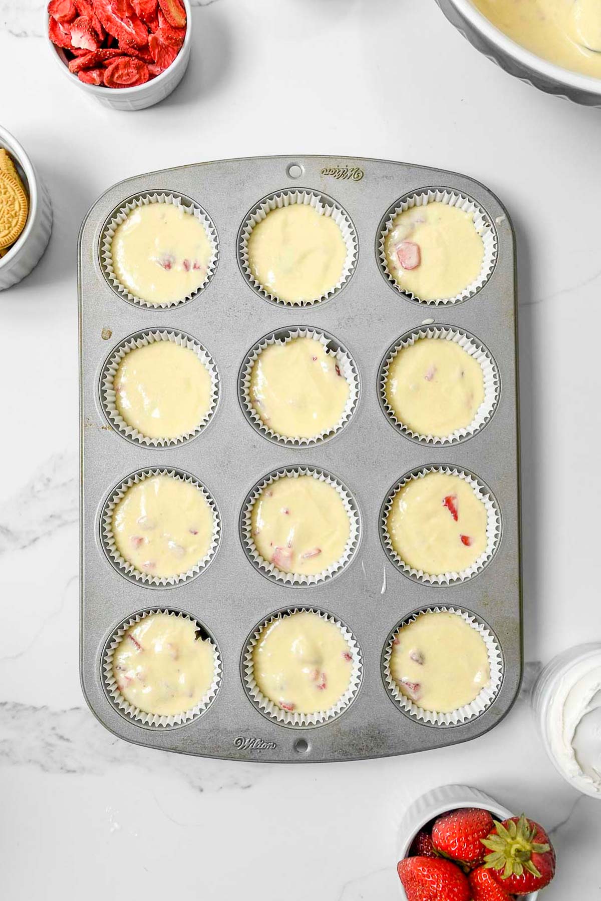Adding muffin batter to muffin tin with paper liners.