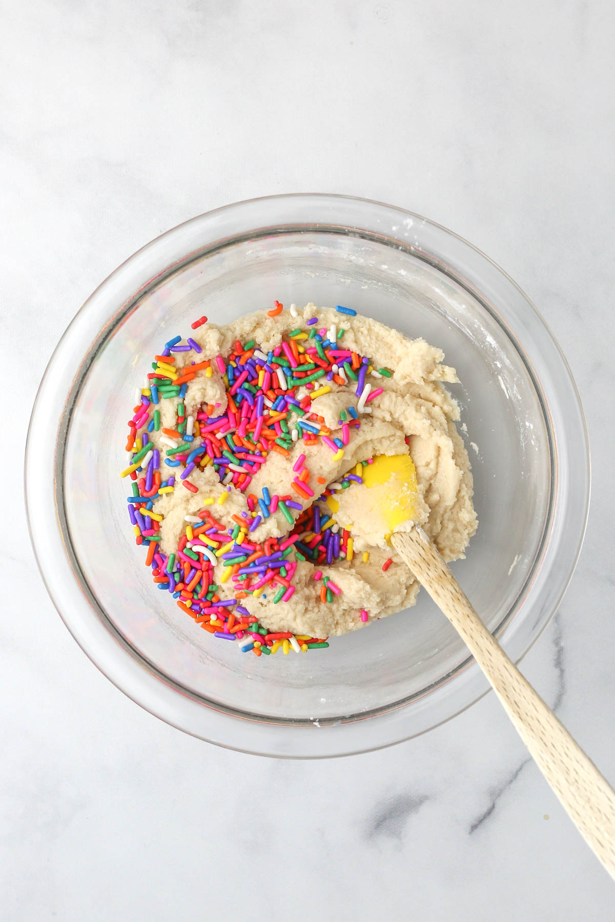 Mixing rainbow sprinkles into the edible sugar cookie dough batter.